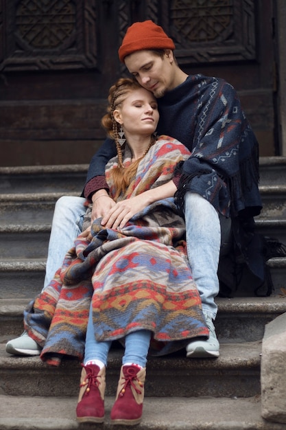 Foto vertical, chico pelirrojo y chica con ropa inusual, pareja de enamorados en la calle.