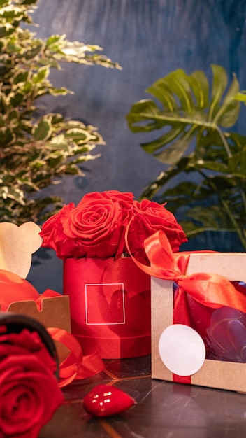 Foto vertical de la composición de la fotografía del producto con una caja de regalo y un jarrón de rosas rojas copia espacio