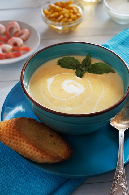 Foto vertical da tigela de sopa de creme com manjericão e pão