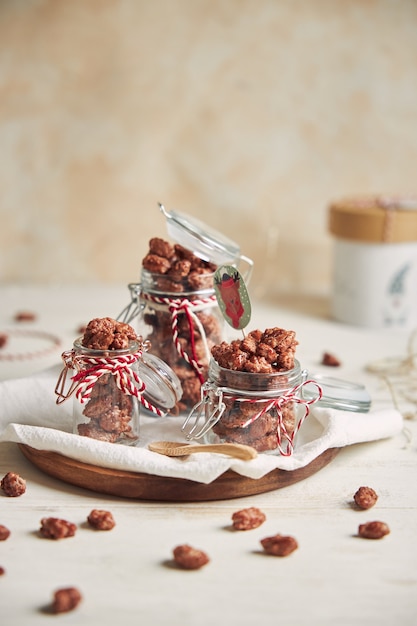 Foto vertical de deliciosas amêndoas torradas de Natal em uma jarra em uma placa de madeira