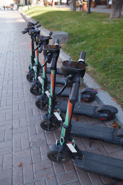 Foto vertical de e-scooters alinhadas, prontas para serem alugadas para passeios