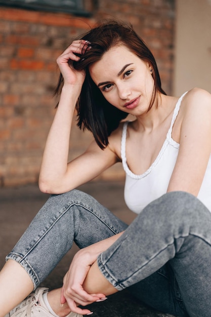 Foto vertical de garota de jeans e camiseta branca com cabelo curto fluindo para a câmera