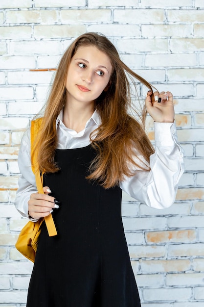 Foto vertical de jovem estudante esticando o cabelo e parece feliz foto de alta qualidade