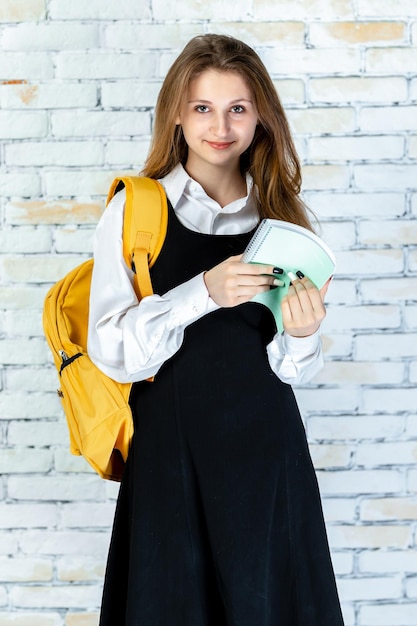 Foto vertical de jovem estudante segurando seu notebook e sorrindo Foto de alta qualidade