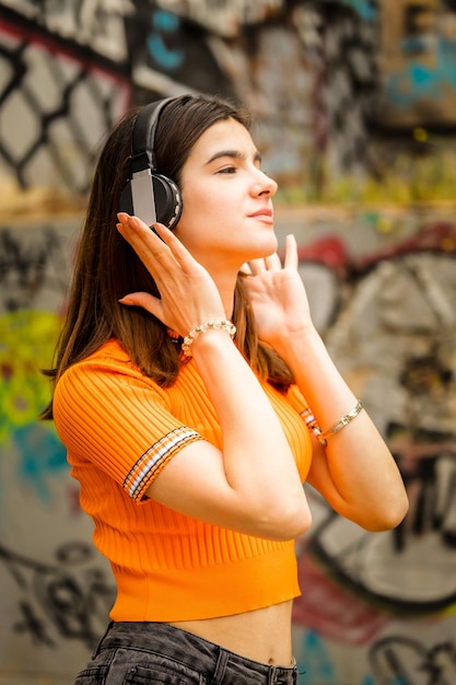Foto vertical de jovem usando fones de ouvido na rua