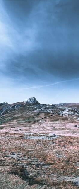 Foto vertical de terreno rochoso montanhoso em um dia sombrio, vista panorâmica da natureza