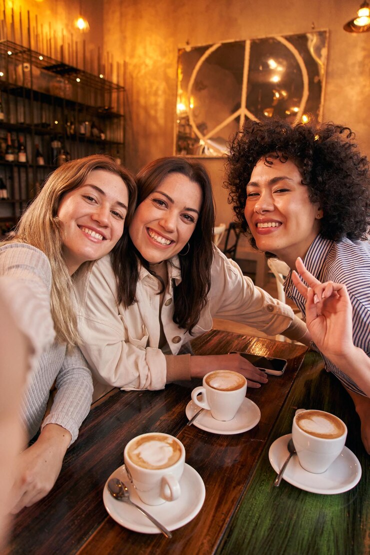 Foto foto vertical de três amigas tirando selfie enquanto se divertem na cafeteria sorrindo felizes