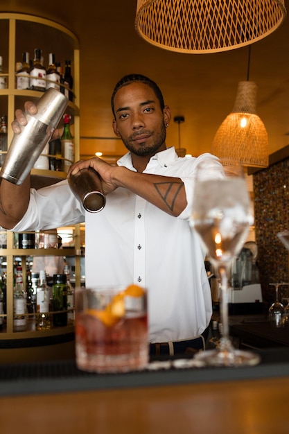 Foto vertical de um barman latino agitando bebidas