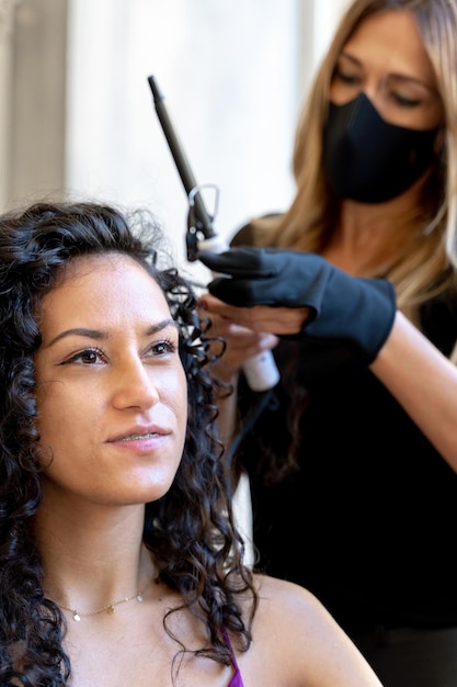 Foto vertical de um cabeleireiro enrolando o cabelo de um cliente