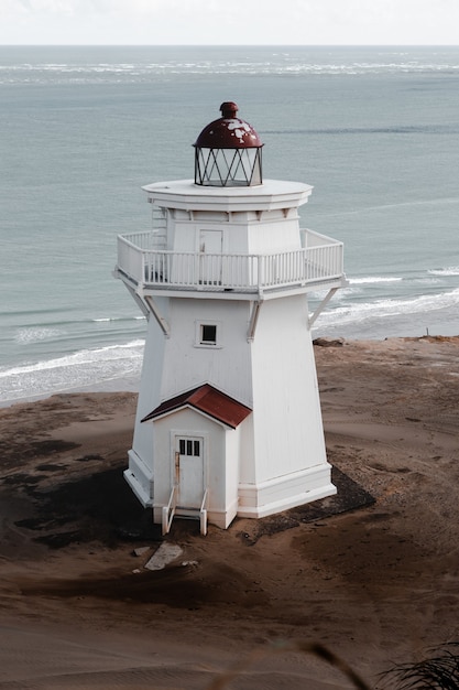 Foto vertical de um farol branco nas montanhas