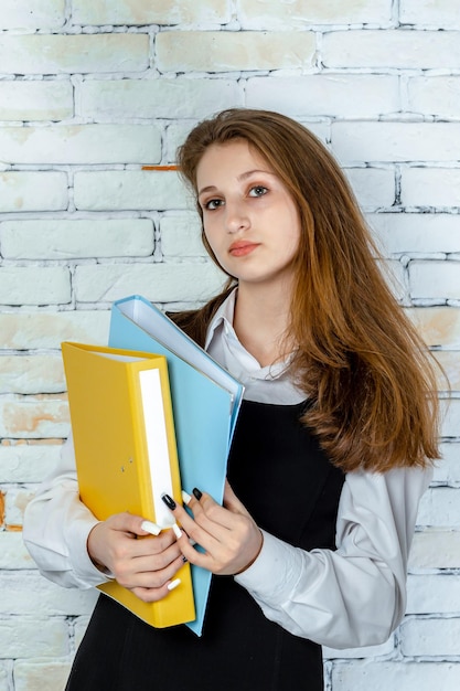 Foto vertical de uma adorável estudante segurando seus cadernos e olhando para a câmera foto de alta qualidade