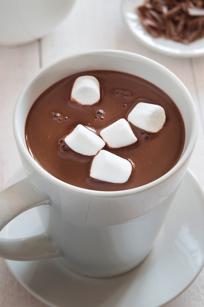 Foto vertical de uma caneca branca de chocolate quente com marshmallow