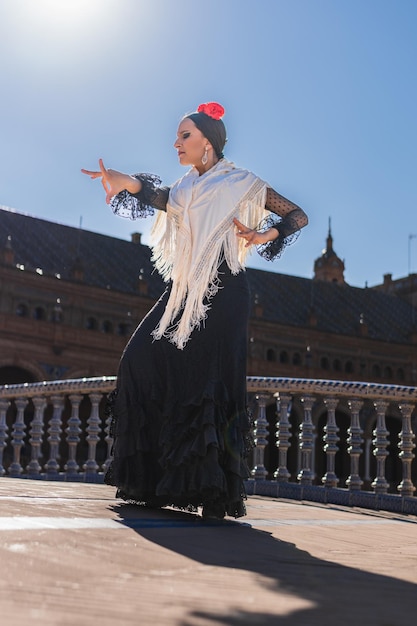 Foto vertical de uma dançarina de flamenco iluminada pelo sol enquanto dança ao ar livre