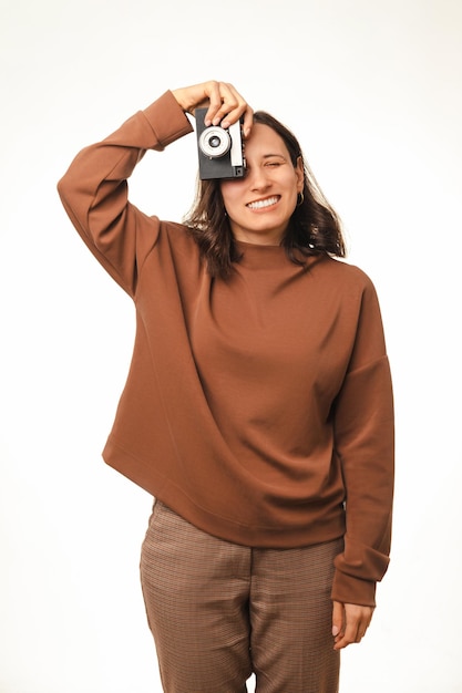 Foto vertical de uma jovem feliz se divertindo com uma velha câmera vintage