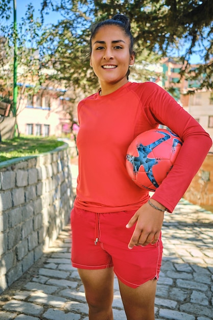 Foto foto vertical de uma jovem jogadora de futebol segurando uma bola de futebol na bolívia américa latina