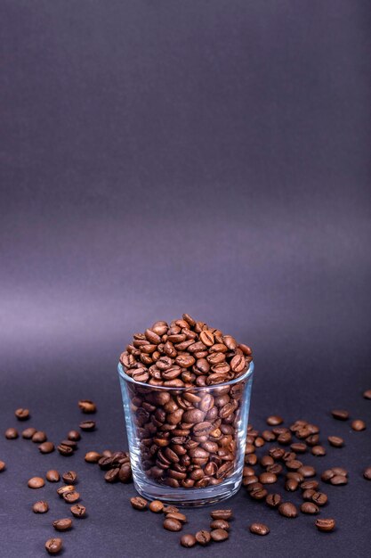 Foto vertical de uma xícara de vidro com grãos de café naturais em um fundo preto contínuo dia internacional do café 1º de outubro