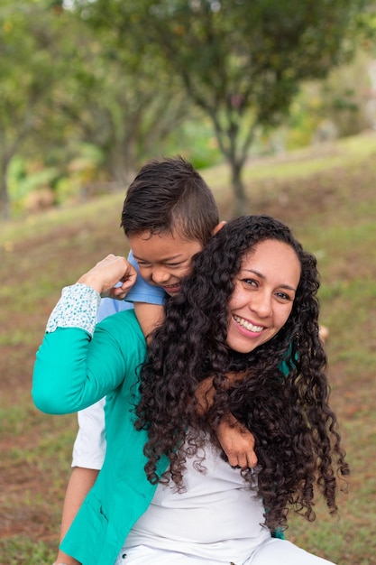 Foto vertical do retrato de uma mulher feliz carregando seu filho sorridente nas costas enquanto brincava