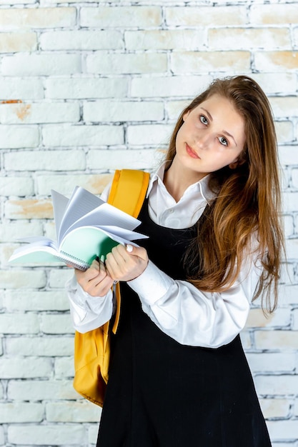 Foto vertical de un estudiante adorable sosteniendo un cuaderno y mirando a la cámara Foto de alta calidad