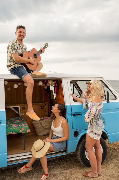 Foto vertical de un hombre tocando la guitarra en una camioneta con un grupo de amigos