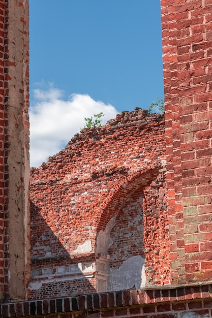 Foto vertical de la iglesia católica destruida. Vista del cielo a través de las paredes de ladrillo rojo.