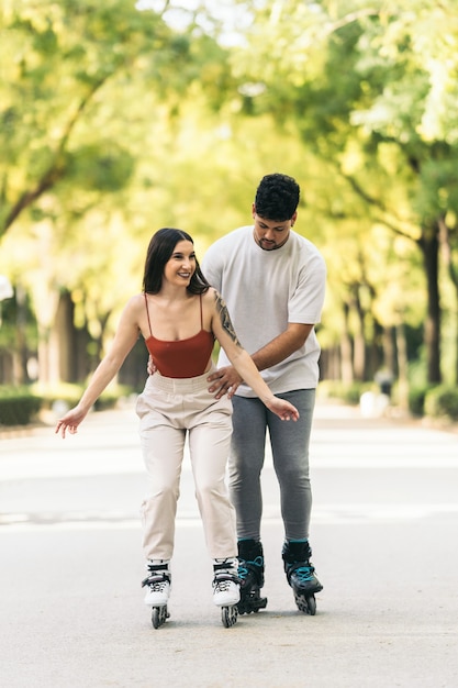 Foto vertical de un joven ayudando a patinar a una mujer en un camino de un parque