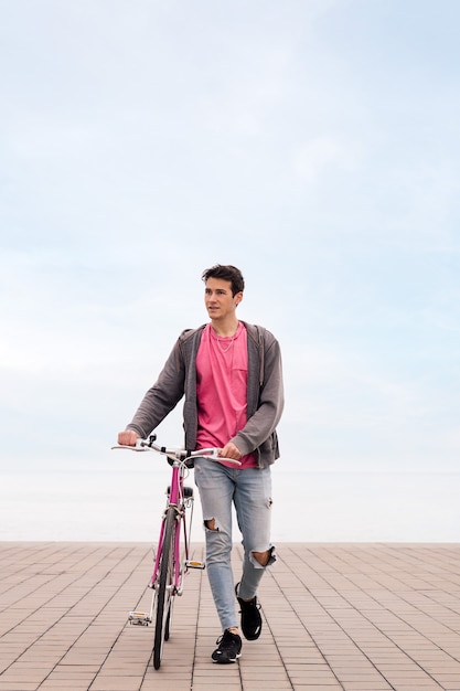 Foto vertical de joven caminando con una bicicleta