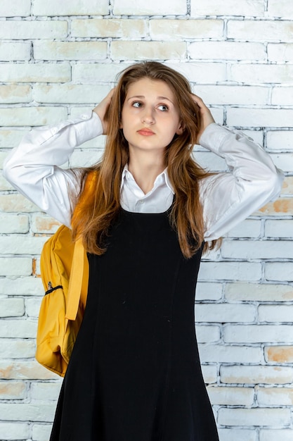 Foto vertical de una joven estudiante llevándose las manos al cabello y parece molesta Foto de alta calidad