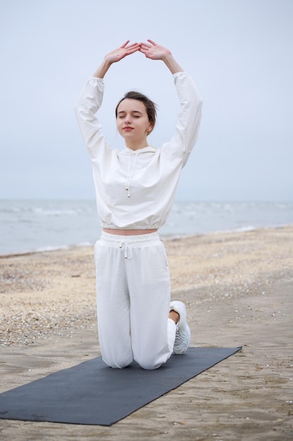 Foto vertical de una joven haciendo meditación en la playa por la mañana foto de alta calidad