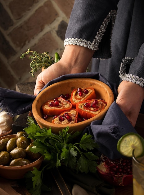 Foto vertical de manos de mujer sosteniendo un plato de peras al horno con nueces de miel y arándanos