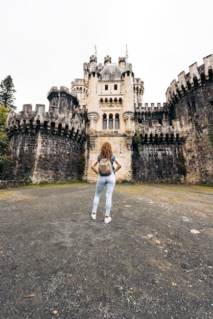 Foto vertical de una mujer frente a un castillo.