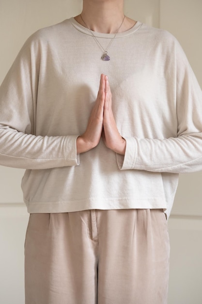 Foto vertical de una mujer de pie irreconocible en posición Namaste.