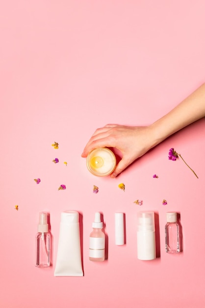 Foto vertical plana con productos de belleza lápiz labial suero crema de manos tóner spray facial