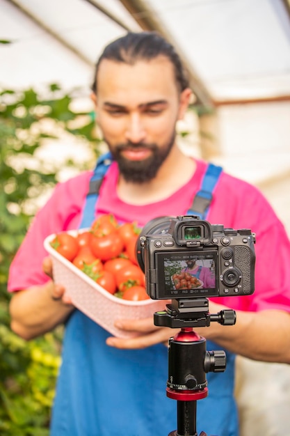 Foto vertical de señorita mostrando tomates a la cámara.