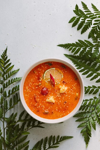 Foto vertical de sopa picante Tom yum entre ramitas de vegetación