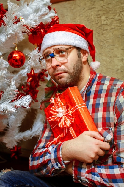 Foto vertical de triste hombre solitario con regalo de Navidad