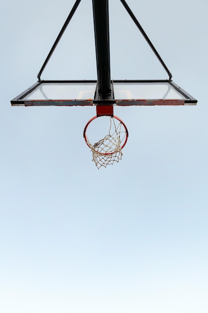 Foto vertical de una vista de aro de baloncesto desde abajo con el cielo de fondo concepto de deporte urbano al aire libre copia espacio para texto