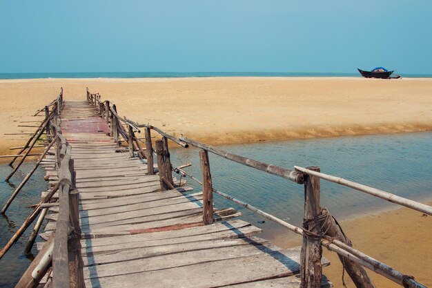 Foto de viaje creativa con playa azul cielo y camino de tablones de madera que conduce lejos