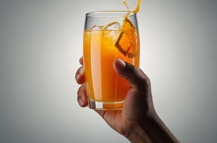 foto vibrante de la mano sosteniendo el vaso de OJ