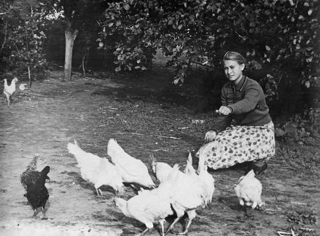 Foto vintage de una joven alimentando gallinas y gallos 1961 URSS