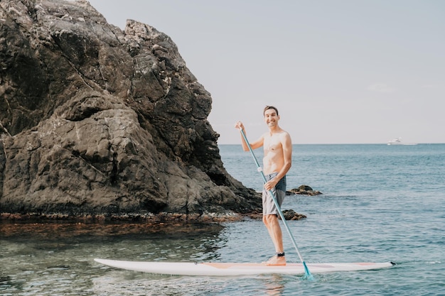 Foto de vista lateral de un hombre nadando y relajándose en el tablero de sup Hombre deportivo en el mar en el Stand Up Paddle Board SUP El concepto de una vida activa y saludable en armonía con la naturaleza