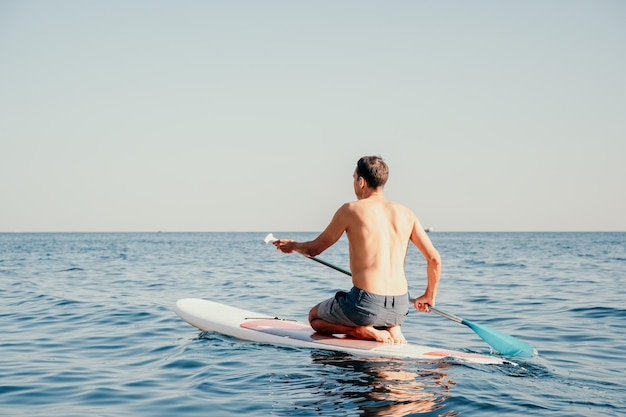 Foto de vista lateral de un hombre nadando y relajándose en el tablero de sup Hombre deportivo en el mar en el Stand Up Paddle Board SUP El concepto de una vida activa y saludable en armonía con la naturaleza