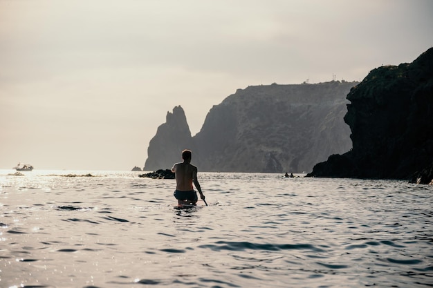 Foto de vista lateral de un hombre nadando y relajándose en el tablero sup hombre deportivo en el mar en el stand