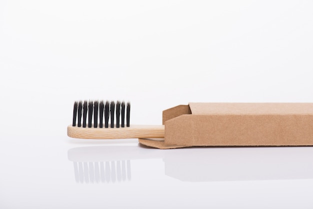 Foto de vista de perfil lateral de primer plano de ecológico embalado en papel de cartón reciclado cepillo de dientes negro aislado sobre fondo blanco.