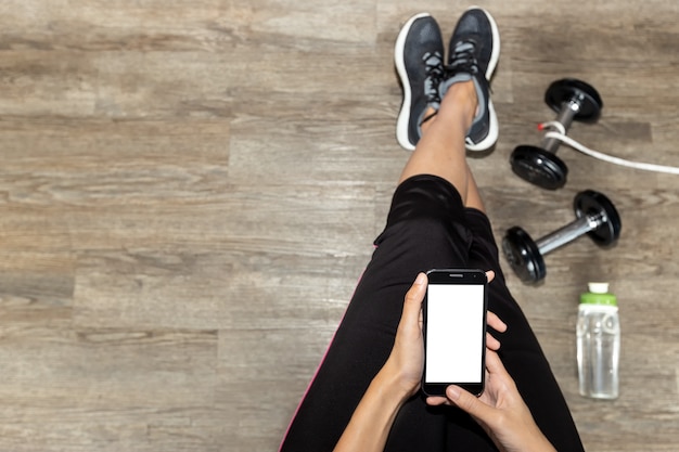 Foto de la vista superior de la aptitud femenina con el teléfono. Concepto del deporte