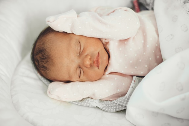 Foto de la vista superior de un bebé recién nacido durmiendo en la cama con ropa linda