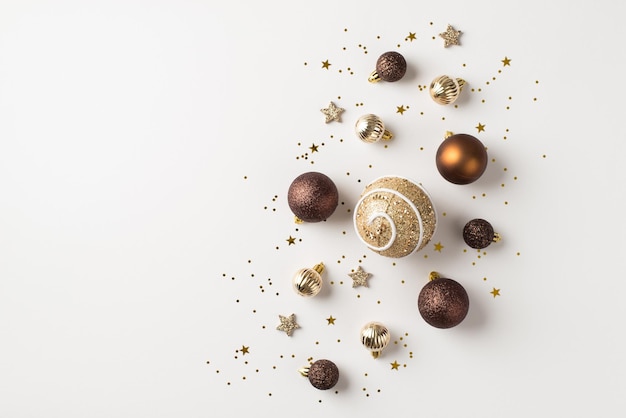 Foto de vista superior de bolas de decoración de árbol de navidad marrón plata y oro estrellas brillantes y confeti sobre fondo blanco aislado con espacio en blanco