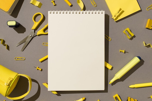 Foto de la vista superior del cuaderno espiral papelería amarilla útiles escolares tijeras rotuladores notas adhesivas sacapuntas borrador clips alfileres y estuche de lápices sobre fondo gris aislado con espacio de copia