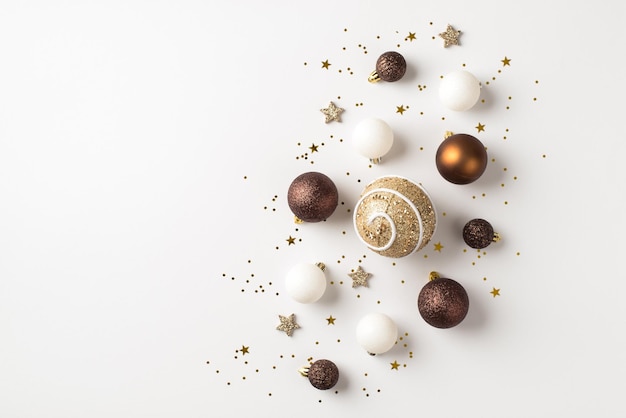 Foto de vista superior de decoraciones de árbol de navidad marrón blanco y dorado bolas estrellas brillantes y confeti sobre fondo blanco aislado con espacio en blanco