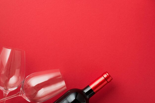 Foto de la vista superior de las decoraciones del día de san valentín dos copas de vino y una botella de vino sobre fondo rojo aislado con espacio vacío