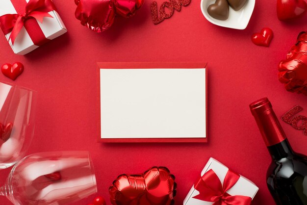 Foto de la vista superior de las decoraciones del día de san valentín tarjetas de papel cajas de regalo globos en forma de corazón dulces corazones pequeños en dos copas de vino y una botella de vino sobre fondo rojo aislado con espacio en blanco
